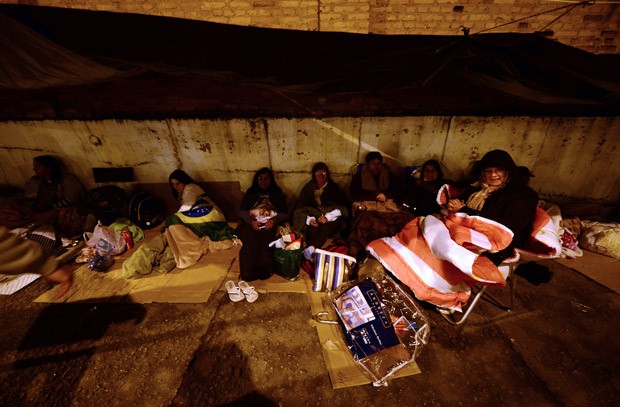 Pessoas tentam se proteger do frio com lonas (Foto: Christophe Simon/AFP)