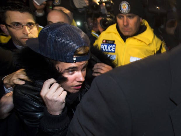 Justin Bieber é cercado por policiais e jornalistas ao se apresentar à polícia nesta quarta-feira (29). (Foto: Nathan Denette/The Canadian Press/AP)
