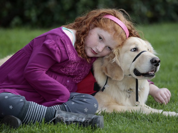 Alyssa Howes, de 11 anos, abraçada ao cão Flint, que é seu fiel escudeiro e vigilante noturno (Foto: Damian Dovarganes/AP)