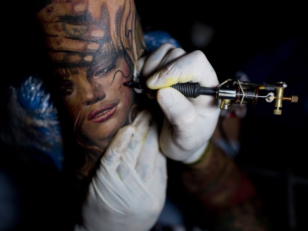 Tatuador Lisandro Libaak tatua uma mulher no braço de Gaspar Obregon (Foto: Natacha Pisarenko/AP)
