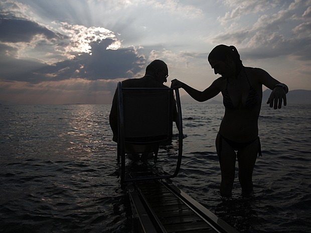 Lefteris Theofilou, que sofre de paraplegia, é ajudado pela mulher, Eleni, de 37 anos, que tem paralisia cerebral (Foto: Yorgos Karahalis/Reuters)