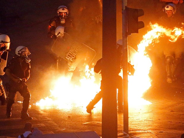 Policiais passam por chamas durante confronto com um pequeno grupo de manifestantes anti- austeridade em frente ao parlamento em Atenas, na Grécia  (Foto: Jean-Paul Pelissier/Reuters)