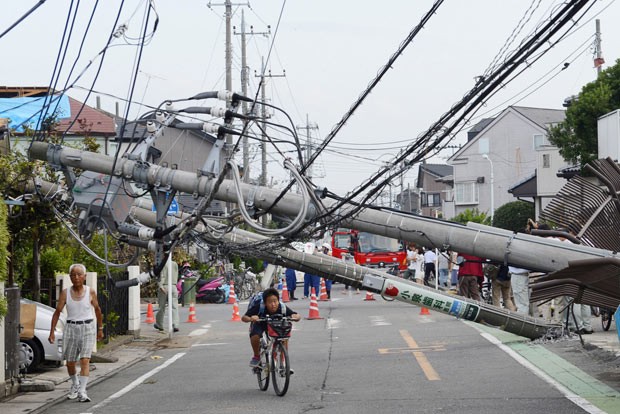 Garoto anda de bicicleta em meio à destruição em Koshigaya nesta segunda-feira (2) (Foto: Kyodo/AP)
