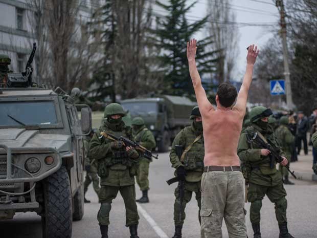 Ucraniano sem camisa protesta na frente de soldados em uniformes não marcados na periferia de Sevastopol, na Ucrânia. (Foto: Andrew Lubimov / AP Photo)