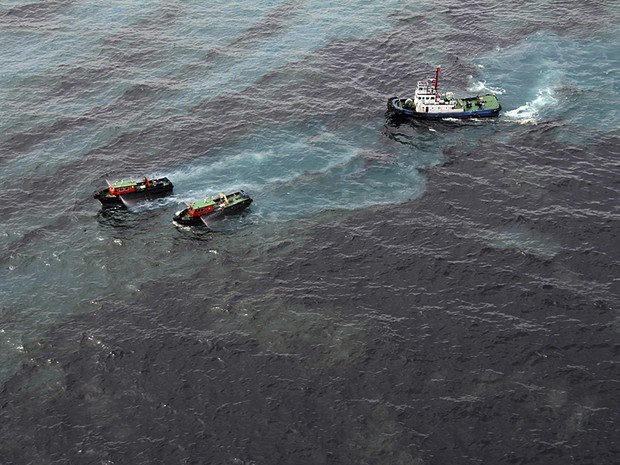 Vazamento de óleo, imagem de embarcações limpando óleo derramado no mar 