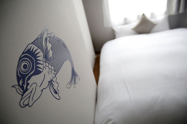 Carpa pintada na parede de um dos hotéis econômicos do Japão; quartos são minúsculos, mas têm decoração moderna e melhor serviço que hotéis-cápsula (Foto: Yuya Shino/Reuters) Carpa pintada na parede de um dos hotéis econômicos do Japão; quartos são minúsculos, mas têm decoração moderna e melhor serviço que hotéis-cápsula (Foto: Yuya Shino/Reuters)