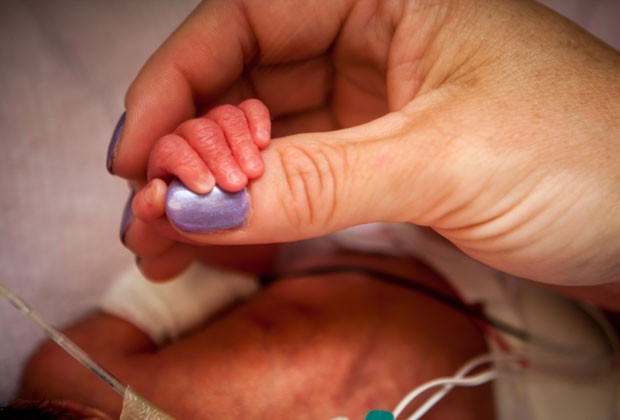 Enfermeira segura a mão de um dos bebês (Foto: Hospital da Universidade de Utah/AP)