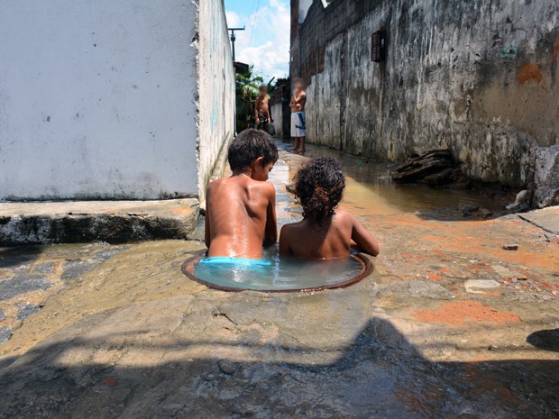 Crianças são flagradas brincando dentro do bueiro onde acontece o vazamento (Foto: Walter Paparazzo/G1)