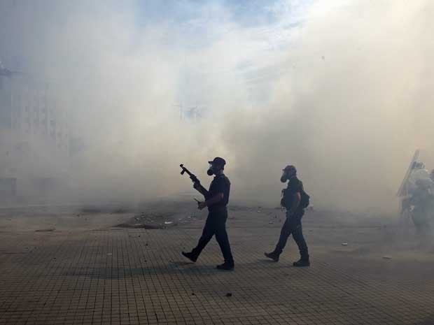Policiais em meio à fumaça do gás lacrimogêneo. (Foto: Thanassis Stavrakis / AP Photo)
