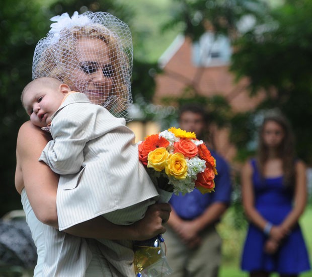 Christine Swidorsky carrega seu filho Logan no colo enquanto entra na cerimônia de seu casamento em Jeannette, na Pensilvânia, no sábado (3) (Foto: Eric Schmadel/Tribune-Review/AP)