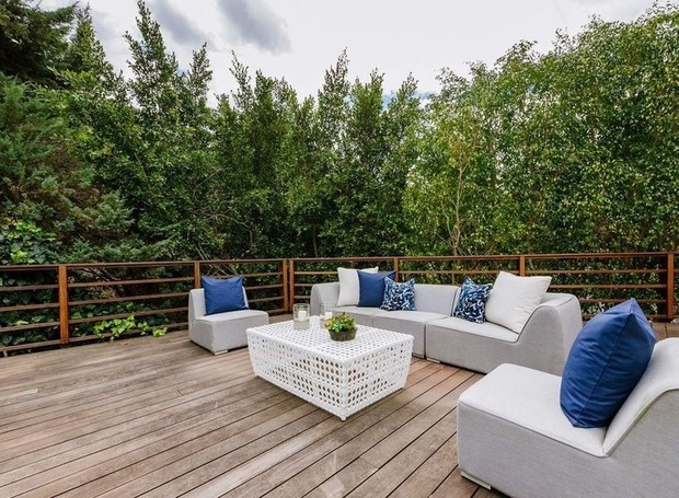 Um deck de madeira é cercado por arbustos que criam uma área de relaxamento com privacidade (Foto: Homes.com)