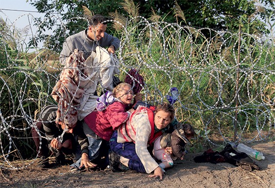 2. Famílias atravessam a cerca farpada na fronteira da Hungria  (Foto: Reuters/Bernadett )