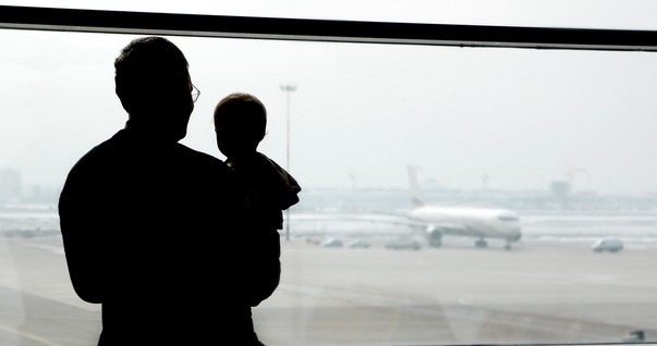 Pai com bebê no colo em um aeroporto (Foto: Shutterstock)