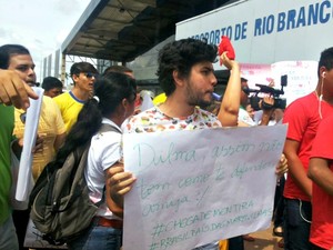 Manifestante exibe cartaz no aeroporto de Rio Branco durante chegada de Dilma (Foto: Janine Brasil/G1)