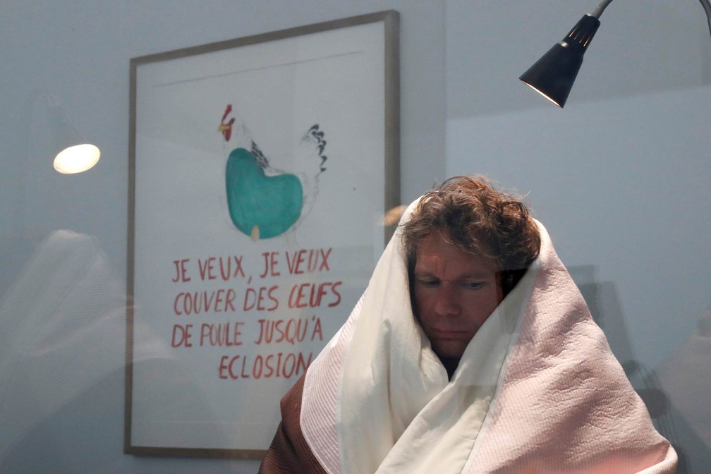O artista francês Abraham Poincheval é visto dentro de um vivário no primeiro dia da performance artística em que pretende chocar ovos de galinha com o calor de seu corpo, no Museu Palais de Tokyo em Paris, na França. O período de incubação esperado é de 21 a 26 dias (Foto: Abraham Poincheval/Reuters)