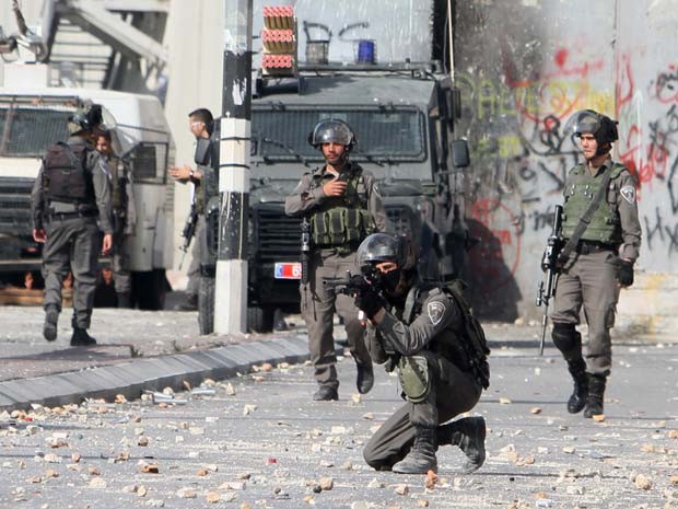 Soldados israelenses apontam armas contra palestinos nesta terça-feira (6) em Belém (Foto: AFP PHOTO / MUSA AL-SHAER)