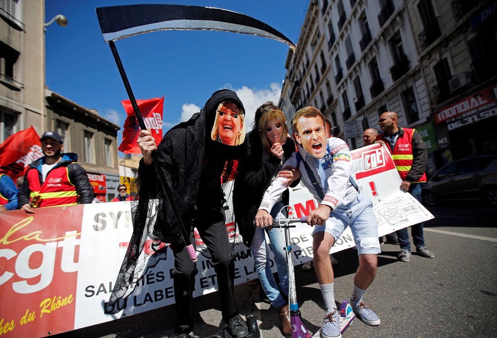 Manifestantes usam máscaras dos candidatos à presidente da França, Marine Le Pen (à esquerda) e Emmanuel Macron (à direita), além de máscara da mulher dele, Brigitte (ao centro), na tradicional marcha do Dia do Trabalhador de Marselha, nesta segunda-feira, dia 1º de maio de 2017 (Foto: Jean-Paul Pelissier/Reuters)