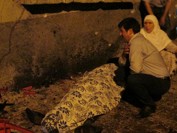 Homem chora ao lado de vítima de explosão em casamento em Gaziantep, na Turquia (Foto: Ihlas News/Reuters)