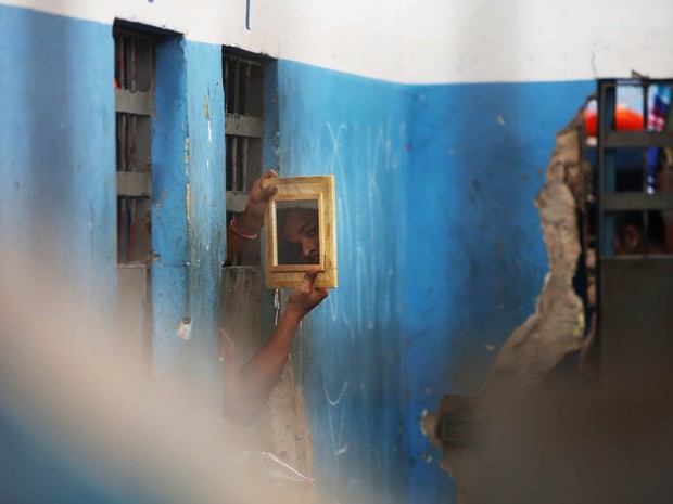 Presidiário usa um espelho para observar visitantes que adentram o Complexo Penitenciário de Pedrinhas, em São Luís (MA) (Foto: Mario Tama/Getty Images)