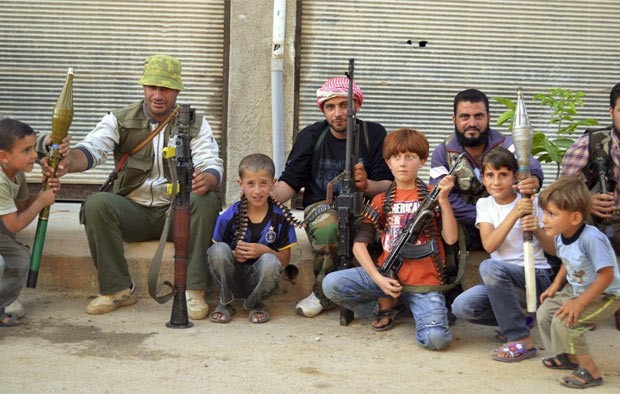 Soldados do exército livre da Síria posam com armas e crianças na cidade de Kfar Nubul, a noroeste da província de Idlib. Confrontos com rebeldes no oeste da Síria mataram 4 civis nesta terça (5) (Foto: AFP)