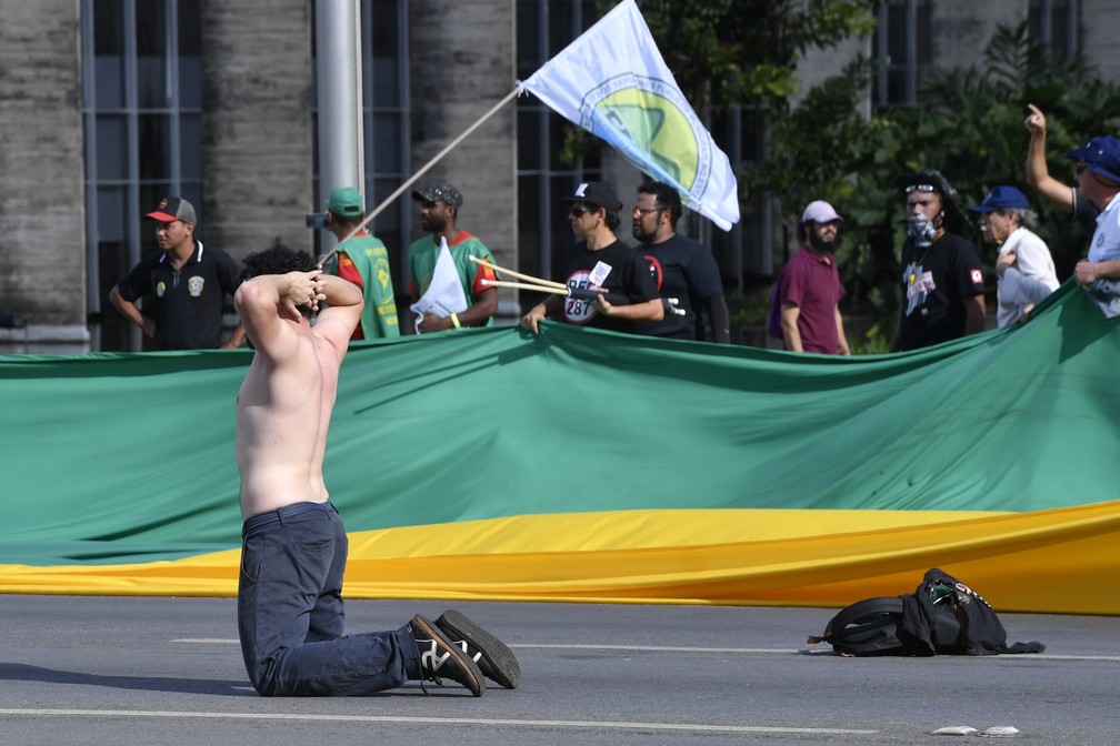 Um manifestante se ajoelha durante protesto contra Michel Temer, em Brasília (Foto: Mateus Bonomi/AFP)