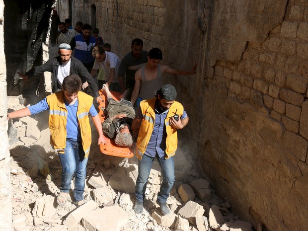 Membros da Defesa Civil síria carregam ferido após bombardeio em Alepo (Foto: Reuters/Abdalrhman Ismail)