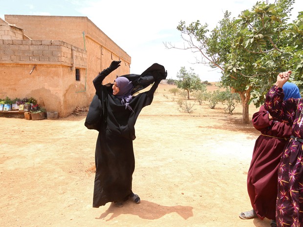 Mulher tira o niqab (véu preto que cobre todo o rosto, menos os olhos) logo após sua cidade ser libertada do Estado islâmico  (Foto: Rodi Said/Reuters)