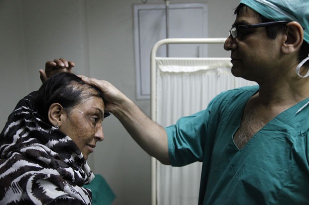 O mdico Asim Shahmalak examina uma das pacientes vtima de ataque de cido que ele operou no Paquisto (Foto: Shakil Adil/AP Images for Crown Clinic)