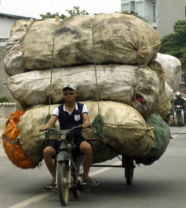 Homem usa motocicleta para transportar carga enorme de materiais recicláveis para vilarejo próximo à capital do país (Foto: Kham/Reuters)