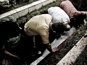 Amigos se debruçam sobre o corpo durante o enterro (Foto: Gabriel Chaim/G1)