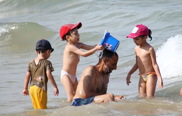 Pai brinca com filhos na região costeira de La Goulette, em Túnis, na Tunísia, em 2 de agosto (Foto: Reuters/Zoubeir Souissi)