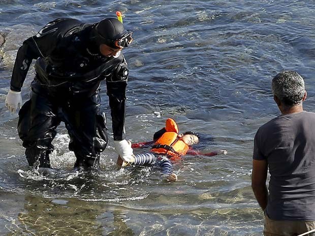 Guarda costeiro da Grécia segura corpor de uma criança imigrante na ilha de Lesbos, na Grécia, após acidente entre barco da polícia grega e bote de refugiados (Foto: REUTERS/Giorgos Moutafis)