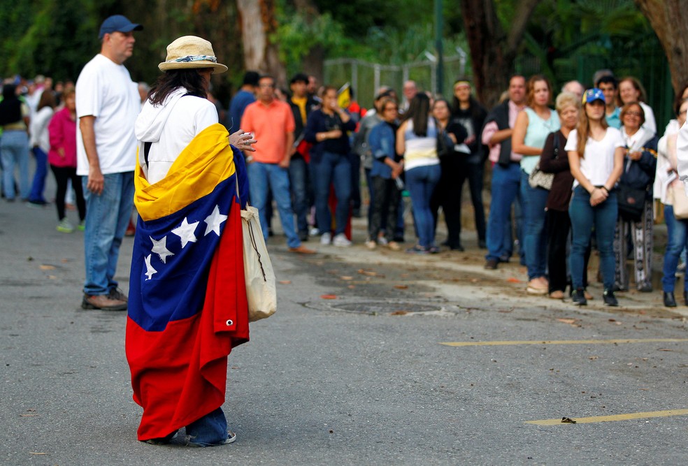Venezuelanos fazem fila para votar no plebiscito contra o presidente Nicolás Maduro, neste domingo (16), em Caracas  (Foto: Christian Veron/ Reuters)