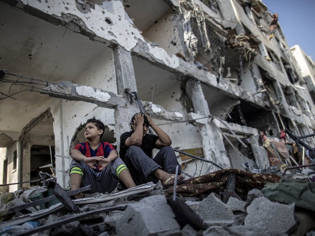 Irmãos palestinos sentados diante do prédio onde moravam na cidade de Beit Hanun, destruída durante conflito entre Israel e Hamas na Faixa de Gaza (Foto: AFP Photo/Marco Longari)