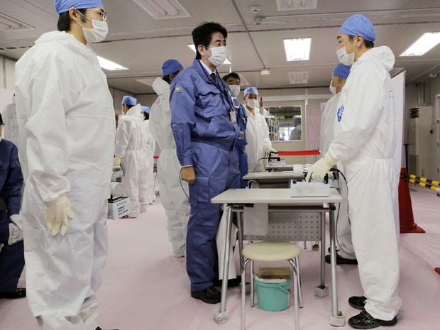 Shinzo Abe, vestido de azul, conversa com cientistas que trabalham na central nuclear de Fukushima (Foto: Itsuo Inouye/AP)