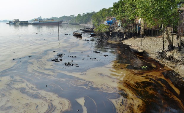 Mancha de óleo é vista nesta sexta-feira (12) no rio Shela, em Bangladesh, após um petroleiro que transportava 357 mil litros de petróleo afundar na região protegida de Sundarbans, em Bangladesh (Foto: Khairul Alam/AP)