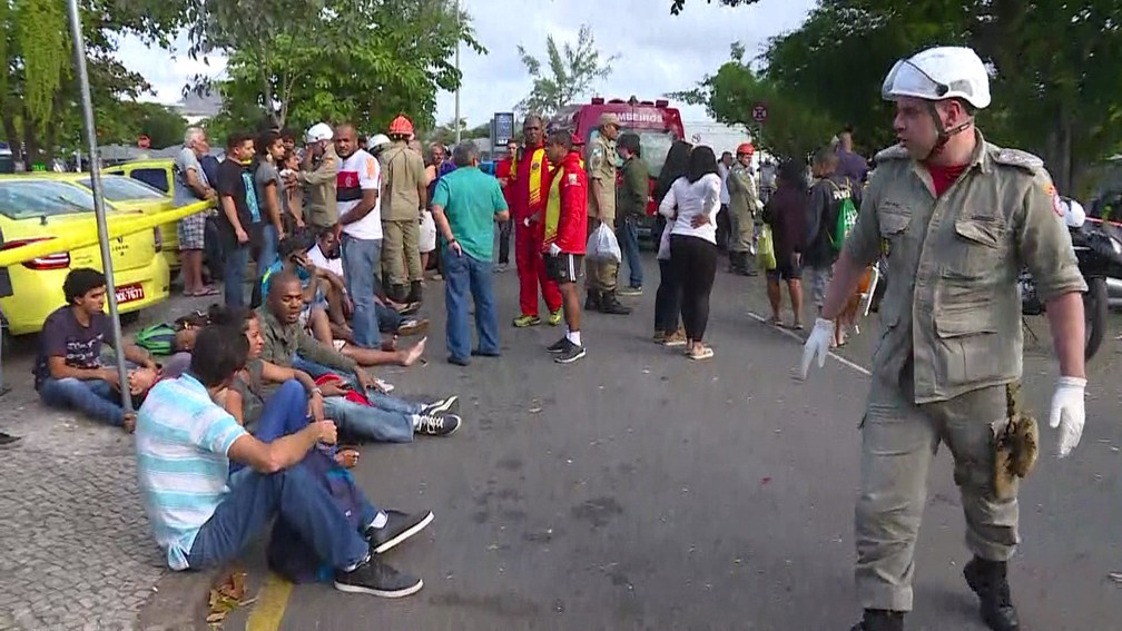 Alguns passageiros ficaram sentados na calçada após acidente com ônibus no Rio (Foto: Reprodução/GloboNews)