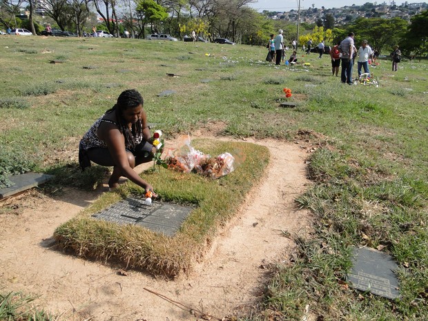 Fabiana Aparecida Machado Silva coloca flores no túmulo dos pais (Foto: Alex Araújo / G1)
