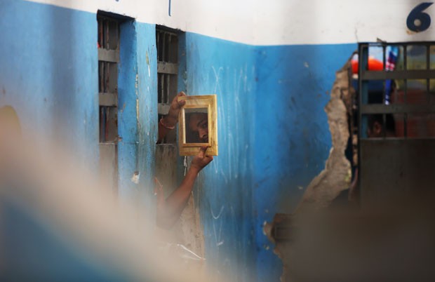 Presidiário usa um espelho para observar visitantes que adentram o presídio de Pedrinhas (Foto: Mario Tama/Getty Images)