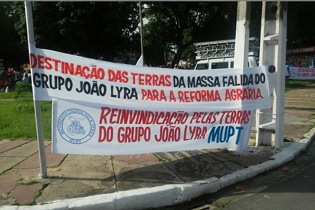 Com faixas, manifestantes pediam que as terras da massa falida do grupo João Lyra sejam destinadas à reforma agrária (Foto: Lucas Leite/G1)