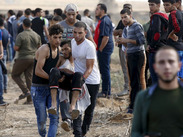 Palestinos carregam um manifestante ferido que foi baleado por soldados israelenses durante confrontos perto da fronteira israelense no nordeste de Gaza. Seis palestinos morreram  (Foto: Mohammed Salem/Reuters)