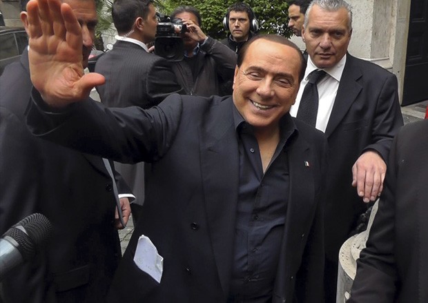 Silvio Berlusconi acena para simpatizantes do lado de fora de sua residência em Roma. O ex-primeiro ministro afirmou que finalmente a Itália teria um governo, pouco antes do anúncio feito por Enrico Letta (Foto: AP)