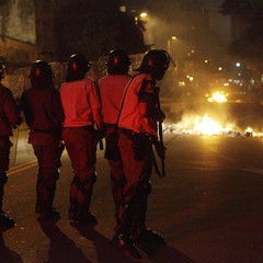 Policiais se posicionam próximo a uma barricada de fogo  (Foto: AP Photo/Nelson Antoine)