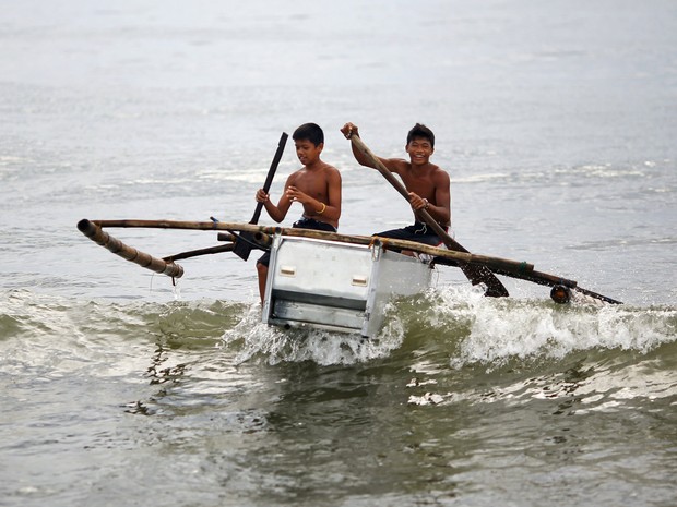 Meninos conduzem barco feito de uma geladeira quebrada e bambu na praia em Tanauan, nas Filipinas. Depois de perder os seus barcos e casas no tufão Haiyan, os pescadores começaram a construir barcos com materiais encontrados na praia. (Foto: Damir Sagolj/Reuters)
