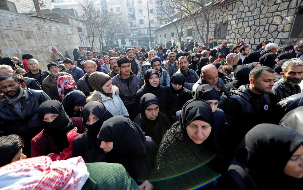 Civis esperam do lado de fora de um centro de polícia para visitar parentes que precisaram deixar distritos no leste de Aleppo, na Síria  (Foto: Omar Sanadiki/ Reuters)