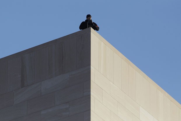 Guarda observa e mantém a segurança de cima de um prédio o desfile em Washington DC. (Foto: Gary Cameron/Reuters)