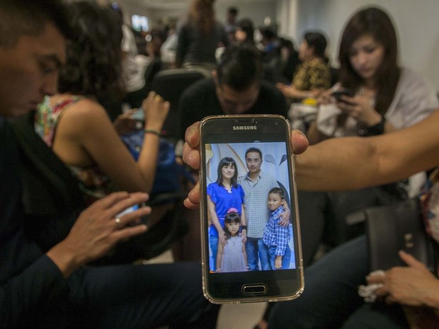Parente no aeroporto de Surabaya mostra foto de família que diz que estava viajando no avião da AirAsia que desapareceu neste domingo (28) (Foto: AFP Photo / Juni )