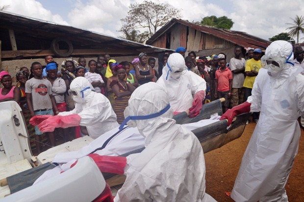  Profissionais da saúde carregam corpo de homem suspeito de ter morrido de ebola em um vilarejo próximo de Monróvia, na Libéria (Foto: AP Photo/Abbas Dulleh)