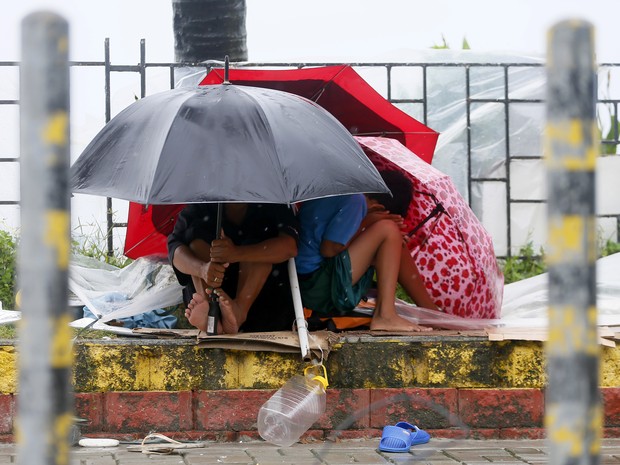 Pessoas tentam se abrigar dos ventos e da chuva em Manila neste domingo (18) (Foto: AP Photo/Bullit Marquez)