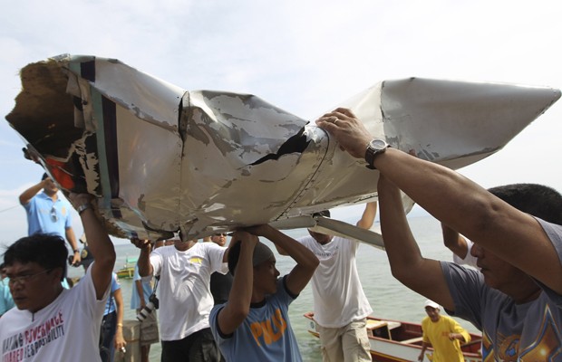 Homens carregam pedaços do avião no qual estava o ministro filipino Jesse Robredo (Foto: AP Photo/Malacanang Photo Bureau, Jay Morales)